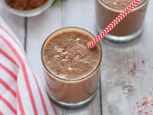 A tall glass filled with a creamy chocolate smoothie, topped with a sprinkle of cinnamon and a straw for sipping